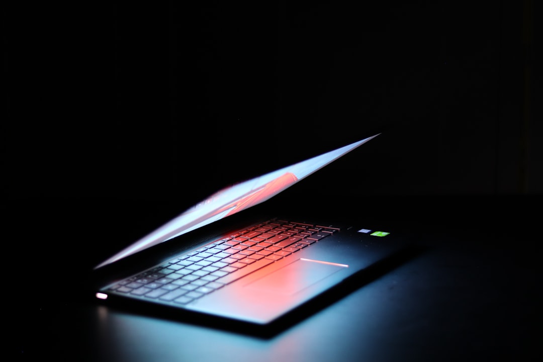 A partially open laptop in a dark setting, emitting soft light.